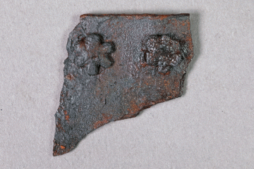ragment eines Blechs mit blütenförmigen Nieten aus Eisen von der Burg Mömbris, Unterfranken, letztes Drittel 14. Jh., Fd.-Nr. 020, H. 3,2 cm, Br. 3,1 cm