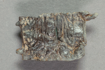 Fragment eines Pilgerzeichens mit sitzender Madonna (?) aus Blei von der Burg Mömbris, Unterfranken, letztes Drittel 14. Jh., Fd.-Nr. 202, H. 1,6 cm, Br. 2.2 cm